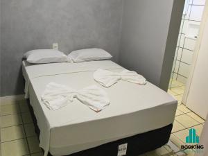 a bed with white towels and a bow tie on it at Estoril Praia de Iracema in Fortaleza +4 photos