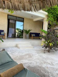a patio of a resort with a bed and chairs at The Garden in Paje