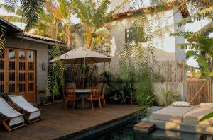 a patio with a table and chairs and an umbrella at Casa Teçá in Guriú