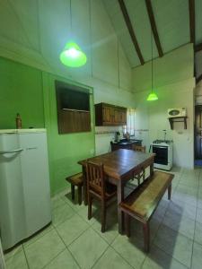 una cucina con tavolo in legno e panca di Chalé Carvalho - Verde a Itapoa Altre 11 foto