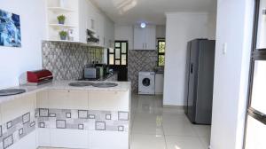 a kitchen with white walls and a refrigerator at Green valley in Amanzimtoti