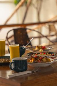 a table with plates of food and cups on it at The Garden in Paje