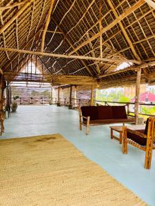 a pavilion with benches and a table and a rug at The Garden in Paje
