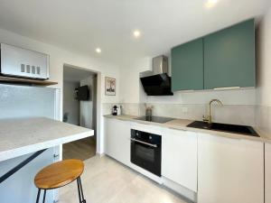 a kitchen with white cabinets and a sink and a stool at Duplex rénové secteur Lac d'Enghien in Saint-Gratien