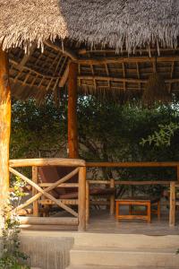 a straw hut with a bench and a chair at The Garden in Paje