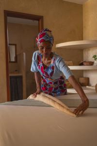 a woman is kneading a piece of cloth on a bed at The Garden in Paje