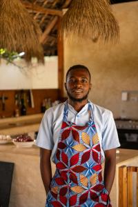 a man wearing a tie standing in a kitchen at The Garden in Paje