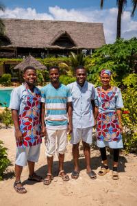a group of four people standing in front of a house at The Garden in Paje