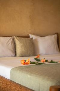 a bed with white pillows and orange flowers on it at The Garden in Paje +37 photos