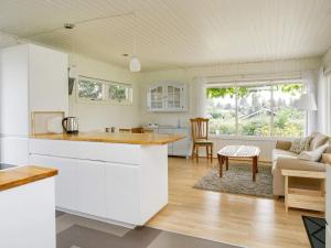 a kitchen with white cabinets and a living room at Charming Cottage by Beach - By Traum Ferienwohnungen in Skibby