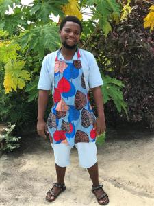 a man wearing a colorful apron is posing for a picture at The Garden in Paje