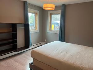 a bedroom with a bed and a tv and two windows at Little holiday home in Yellowknife