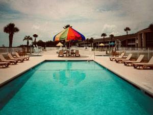 einen Pool mit Stühlen und einem Sonnenschirm in der Unterkunft Cute Cottage with 3 min walk to beach with bikes! in Jekyll Island