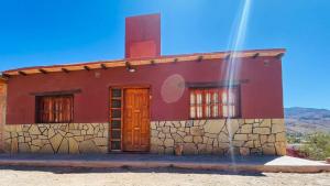 a red house with a red door and a stone wall at El Balconcito de Tilcara in Tilcara
