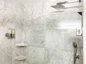 a bathroom with a shower with white marble walls at Chic Victorian Oasis - Oakland Heart in Oakland +17 photos