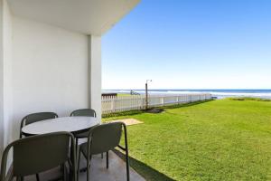 a patio with a table and chairs and the ocean at Absolute Beachfront Apartment 11B in Lennox Head