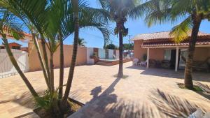 a courtyard with palm trees and a house at Cantinho da Bell in Araruama