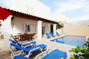 a patio with blue chairs and a swimming pool at Villa Sofia in San Antonio