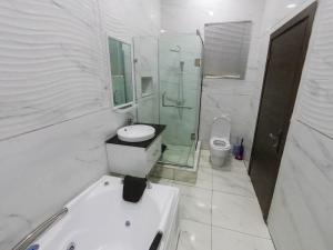 a white bathroom with a sink and a toilet at Hibiscus Empire in Ikuata +10 photos