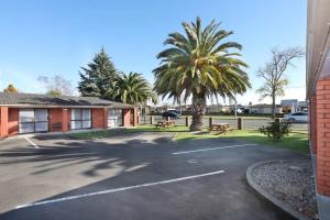 un parcheggio con panchine e una palma di Accommodation Gateway Motel a Palmerston North