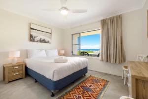 レノックス・ヘッドにあるAbsolute Beachfront Apartment 3Bのベッドと机と窓のある寝室