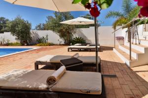 a patio with lounge chairs and an umbrella and a pool at Villa Fuseta 102 T in Fuzeta