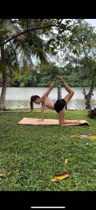 a woman doing a yoga pose in front of the water at riVer in Pelena
