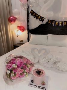 a bed with a cake and pink roses and balloons at The Eden Cat Ba in Cat Ba +68 photos