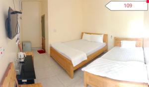 a room with two beds and a television in it at Homstay Sinh thái Cây Sung Mộc Châu in Mộc Châu