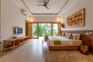 a bedroom with a bed and a desk and a window at Bije Boutique & Gallery in Ubud