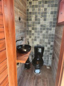 ein Badezimmer mit schwarzer Toilette und Waschbecken in der Unterkunft Vila do Rico in São Gonçalo do Amarante