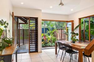 an open dining room with a wooden table and chairs at The Savannah Villa in Port Douglas