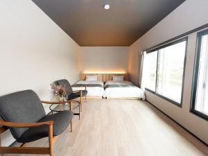 a bedroom with two beds and chairs and a window at IZUMO DOGS by HIYORISTAY in Izumo