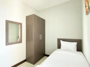 a bedroom with a bed and a cabinet with a mirror at Homey 2BR Apartment Crown Court Executive Condominium By Travelio in Cikarang