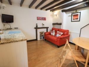 a living room with a red couch and a table at Cobblestone Cottage in Ambleside
