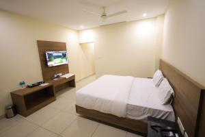 a hotel room with a bed and a television at J S Grand in Yelagiri