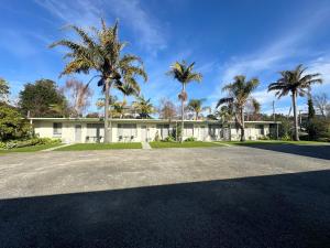 a house with palm trees in front of it at The Silver Bream Motel & Self Contained Units in Mallacoota