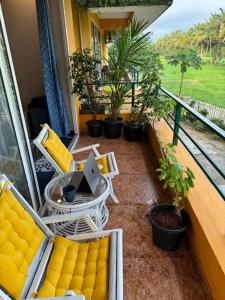 a balcony with chairs and a table with a laptop on it at Bluebell Meadows 2BHK in Varca