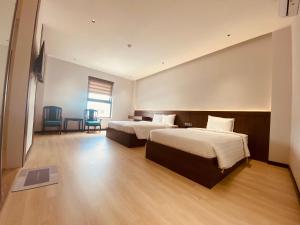 a hotel room with two beds and a table and chairs at Khách Sạn LUCIEN HOTEL Quy Nhơn in Quy Nhon