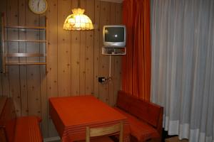 a small room with a table and a tv on the wall at Appartamento Amba 39 in Mezzana