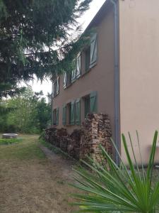 een gebouw met groene ramen en een stapel stenen bij Chez Yves , 200 m du canal , 7 min de Golfech , parking privé et gratuit , rangement vélo fermés in Pommevic