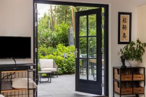 an open door leading to a patio with a television at Casa Black Nature in Holten