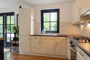 a kitchen with white cabinets and a sink at Casa Black Nature in Holten