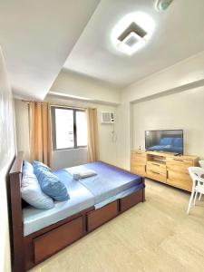 a bedroom with a large bed and a tv at By Trixia BE Apartments, Luxury Studio Apartments, AC, Pool, Gym, near IT Park in Cebu City