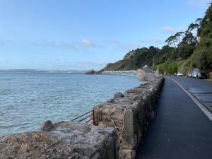 a retaining wall next to the water with a train on it at 1 Ilsham Cottages in Torquay