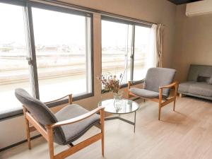 a living room with chairs and a table and windows at IZUMO DOGS by HIYORISTAY in Izumo