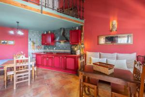cocina con armarios rojos y comedor con mesa en El Tinao De La Petra, en Fuentidueña de Tajo