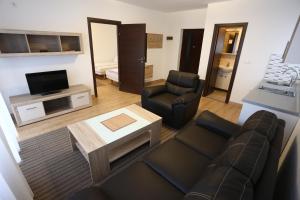 ein Wohnzimmer mit einem Sofa, Stühlen und einem TV in der Unterkunft Apartments Kolonija in Sarajevo