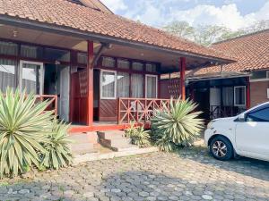 a house with a white car parked in front of it at Pesona Pondok Lembang Mitra RedDoorz in Cikidang 1