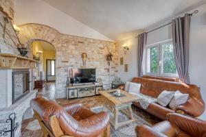 a living room with leather furniture and a stone wall at Ivana in Karpijan in Umag